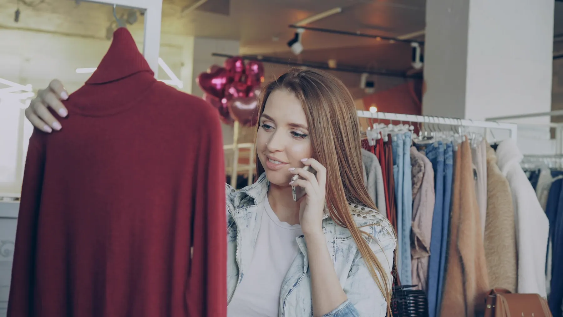 Klientka korzystająca z telefonu podczas wybierania ubrania w prawdziwym sklepie